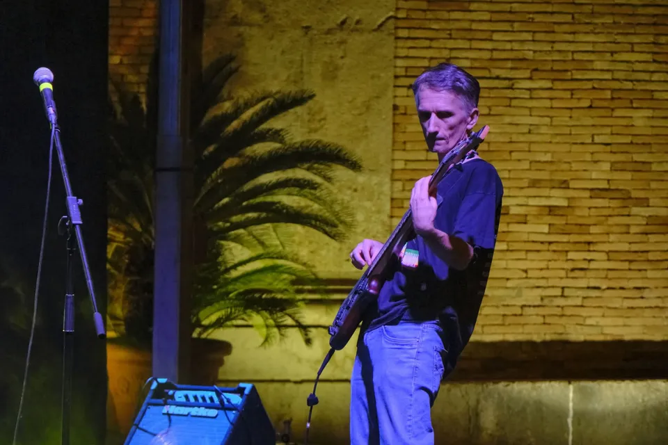 Antonio Lanni al basso su un palco illuminato di blu, davanti a un muro di mattoni